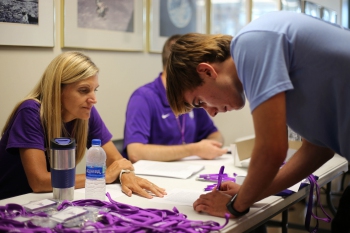 Student signing paper at table